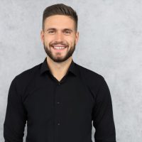 Happy,Brunette,Man,Is,Smiling,At,Camera,Isolated,Over,Gray